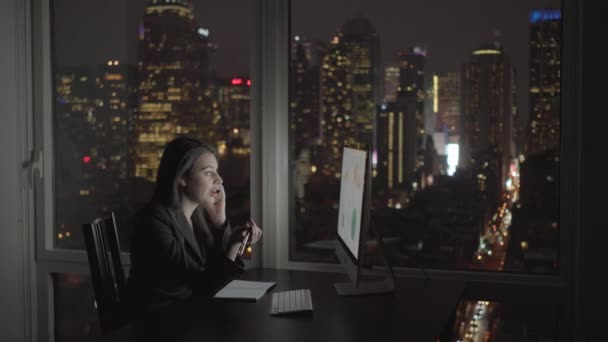 Mujer de negocios trabajando en la computadora y hablando en el teléfono móvil — Vídeo de stock