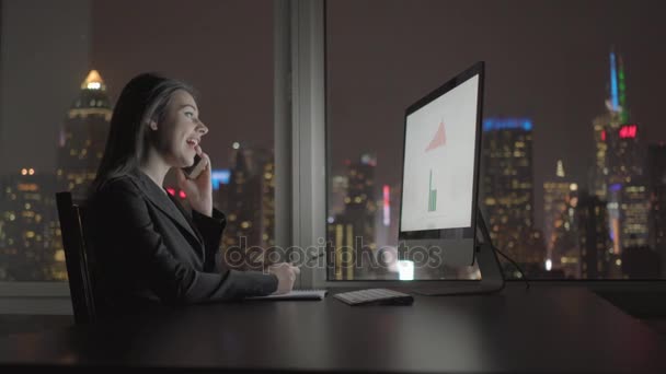 Affärskvinna arbetar med dator och pratar i mobiltelefon — Stockvideo