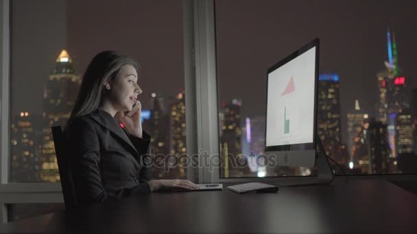 Affärskvinna arbetar med dator och pratar i mobiltelefon — Stockvideo