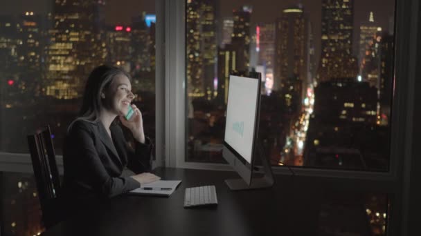 Бізнес-леді працює на комп'ютері і розмовляє на мобільному телефоні — стокове відео
