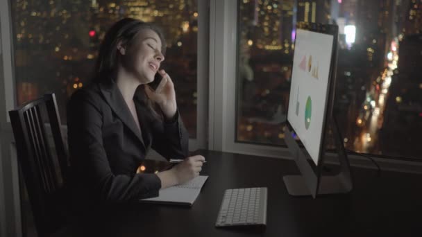 Zakenvrouw werken op de computer en praten op mobiele telefoon — Stockvideo