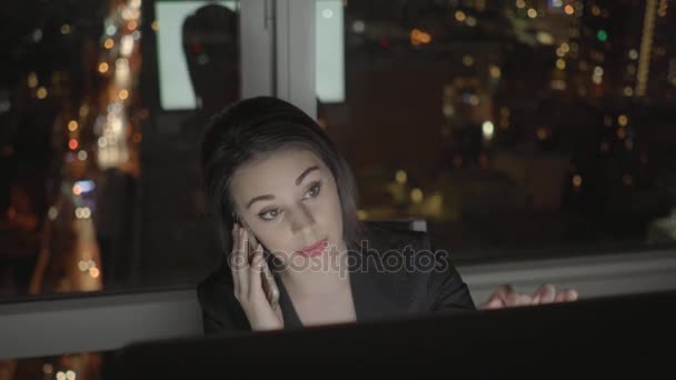 Bilgisayarda çalışarak ve cep telefonu üzerinde konuşurken iş kadını — Stok video