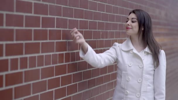 Жінка перед стіною і представляє продукт — стокове відео