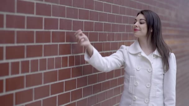 Mujer delante de la pared y la presentación de un producto — Vídeo de stock