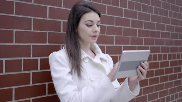 Жінка стоїть на вулиці і використовує планшетний комп'ютер — стокове відео