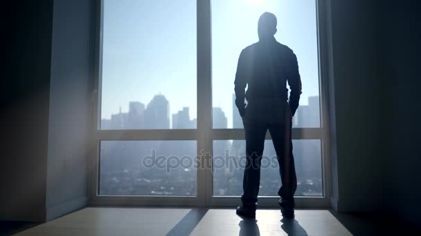 Silhouette of man standing at large window — Stock Video