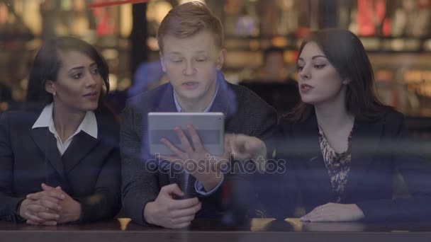 Друзі дивляться на планшетний комп'ютер, розмовляють і розважаються — стокове відео