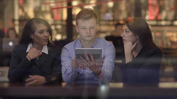 Amigos mirando una tableta, hablando y divirtiéndose — Vídeo de stock