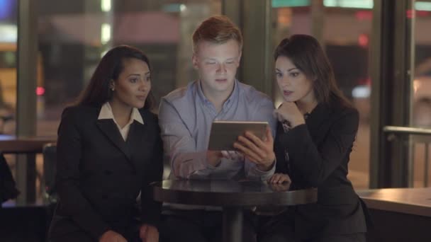 Amigos mirando una tableta, hablando y divirtiéndose — Vídeo de stock