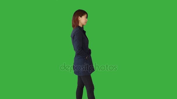 Азіатська жінка стоїть на зеленому фоні — стокове відео