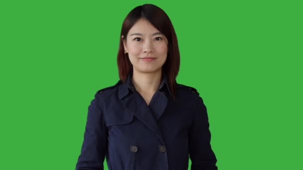 Азиатка стоит на зеленом фоне — стоковое видео