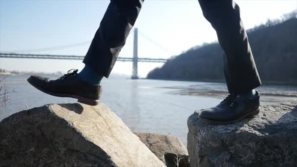 Un joven caminando sobre rocas — Vídeo de stock