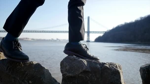 Un joven caminando sobre rocas — Vídeo de stock