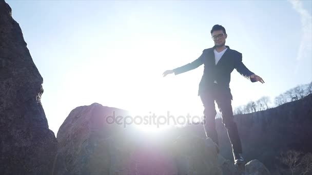 Un joven caminando sobre rocas — Vídeo de stock