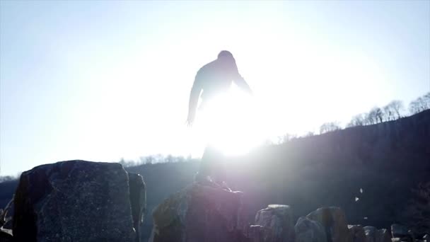 Kayaların üzerinde yürüyen bir genç adam — Stok video