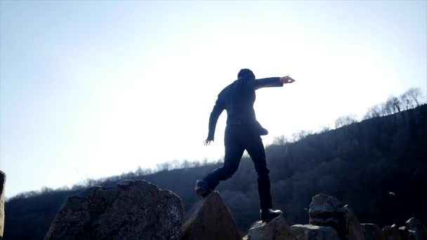 Un joven caminando sobre rocas — Vídeo de stock