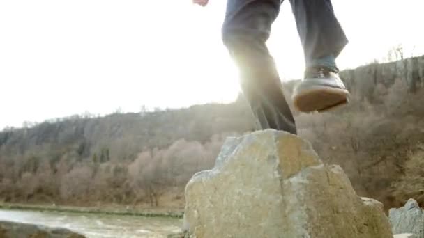 Un joven caminando sobre rocas — Vídeos de Stock