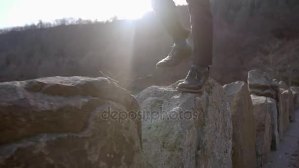 Un joven caminando sobre rocas — Vídeo de stock