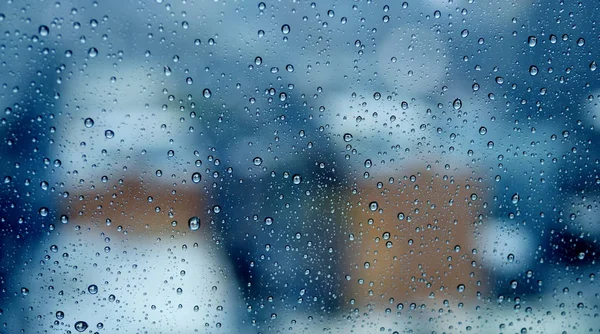 Gotas de lluvia en ventana con ciudad borrosa Imagen De Stock