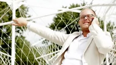 salıncakta rahatlatıcı ve Smartphone'da konuşan adam