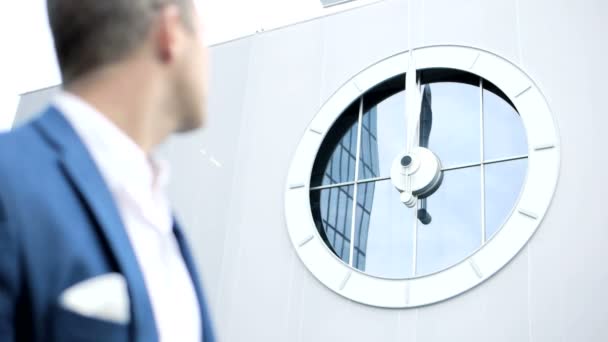 Joven hombre de negocios mirando el reloj en la pared — Vídeos de Stock