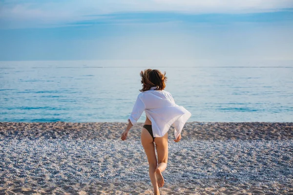 その少女は海に走る。後ろから見た眺め。美しい戦利品日没 ストック写真