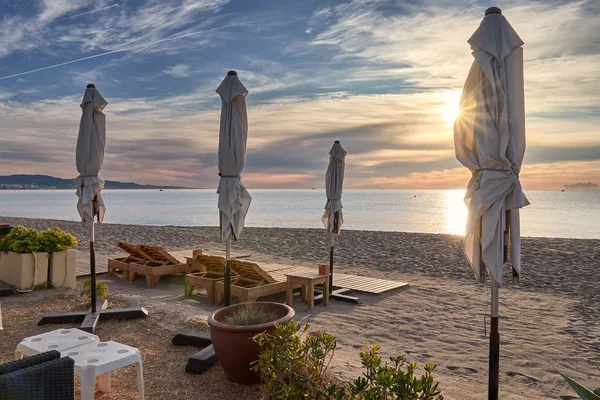 Güneşin doğuşunda güneş şemsiyesi ile plaj şezlongunda — Stok fotoğraf