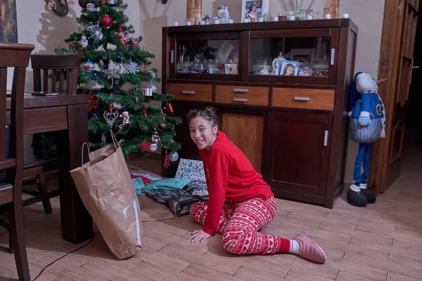 Fille recevant des cadeaux de Noël sous le sapin à sa maison — Photo