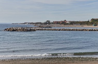Beach with breakwater in Marbella, summer day