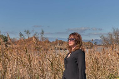 Şık bahar elbisesi içinde şık bir kız. Tarlada güneş ışığı nehrinde koşuyor. Denize yakın.