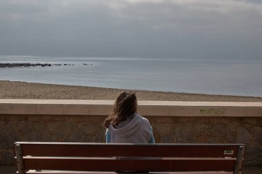 Marbella 'da sahile yakın oturan denizi izleyen kız.