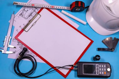 Ultrasonik kalınlık ölçüm cihazı, kalibreler, bir kalem ve miğferle birlikte boş not - antika kontrol için hazır bir müfettişin basit ekipmanı.
