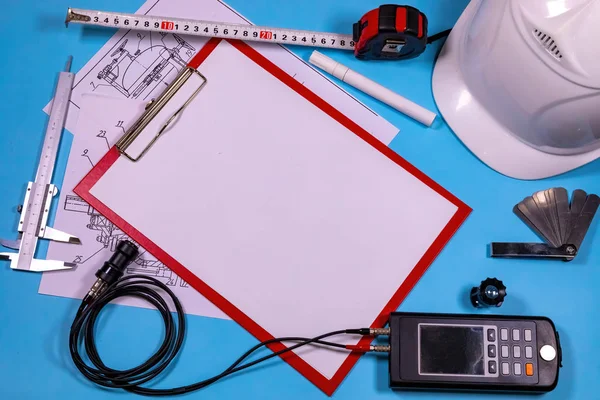 Ultrasonik kalınlık ölçüm cihazı, kalibreler, bir kalem ve miğferle birlikte boş not - antika kontrol için hazır bir müfettişin basit ekipmanı.