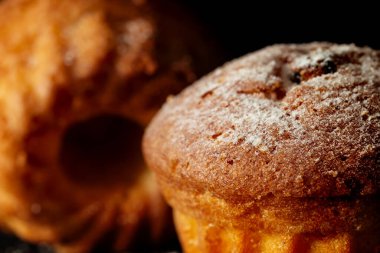 Siyah arka planda pudra şekerli iki fırında kek.