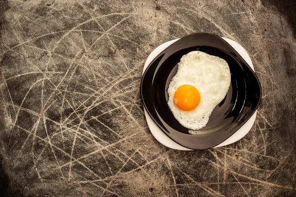用黑白相间的盘子在深色的划痕背景上煎鸡蛋 — 图库照片