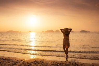 Bir şapka ve kısa elbise mutlu kadın'nde deniz günbatımı sahiptir. Denize, vintage renk arka plan dağlık karstik dağlarda