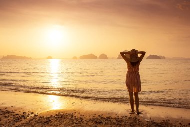 Bir şapka ve kısa elbise mutlu kadın'nde deniz günbatımı sahiptir. Denize, vintage renk arka plan dağlık karstik dağlarda