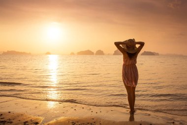 Bir şapka ve kısa elbise mutlu kadın'nde deniz günbatımı sahiptir. Denize, vintage renk arka plan dağlık karstik dağlarda