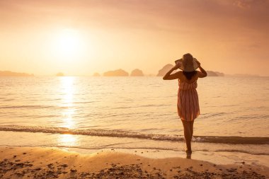 Bir şapka ve kısa elbise mutlu kadın'nde deniz günbatımı sahiptir. Denize, vintage renk arka plan dağlık karstik dağlarda