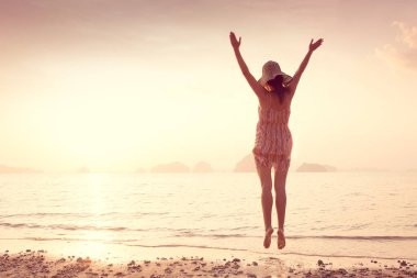 Bir şapka ve kısa elbise mutlu kadın'nde deniz günbatımı sahiptir. Denize, vintage renk arka plan dağlık karstik dağlarda