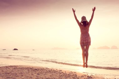 Bir şapka ve kısa elbise mutlu kadın'nde deniz günbatımı sahiptir. Denize, vintage renk arka plan dağlık karstik dağlarda