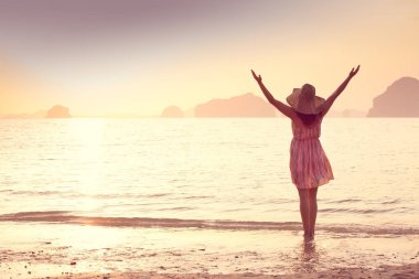 Bir şapka ve kısa elbise mutlu kadın'nde deniz günbatımı sahiptir. Denize, vintage renk arka plan dağlık karstik dağlarda