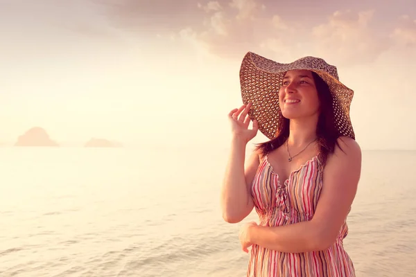 Mujer feliz en un sombrero y vestido corto disfruta en Sea Sunset. En el fondo montañas kársticas montañosas al mar, color vintage — Foto de Stock