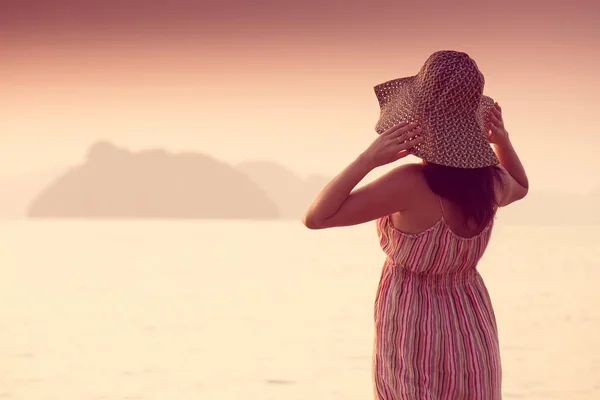 Mujer feliz en un sombrero y vestido corto disfruta en Sea Sunset. En el fondo montañas kársticas montañosas al mar, color vintage — Foto de Stock