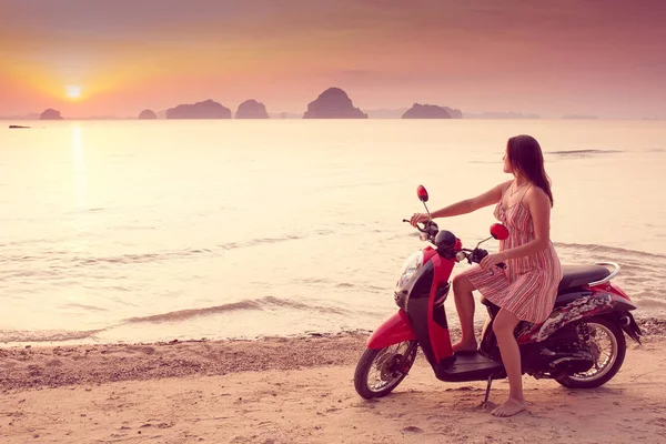 Mujer feliz en vestido corto disfruta en Sea Sunset se sienta en una scooter. En el fondo montañas kársticas montañosas al mar, color vintage — Foto de Stock