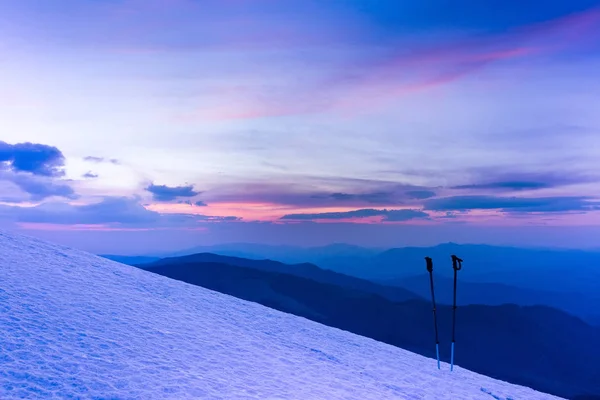 Nascer do sol de inverno colorido nas montanhas. Varas de esqui ou postes de trekking . — Fotografia de Stock