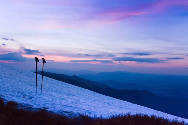 Nascer do sol de inverno colorido nas montanhas. Varas de esqui ou postes de trekking . — Fotografia de Stock