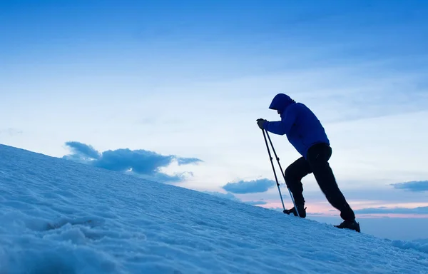 Al crepuscolo un coraggioso sciatore di backcountry raggiunge la vetta della montagna dopo una lunga giornata a piedi nel deserto. Concetto di avventura ed esplorazione . — Foto Stock