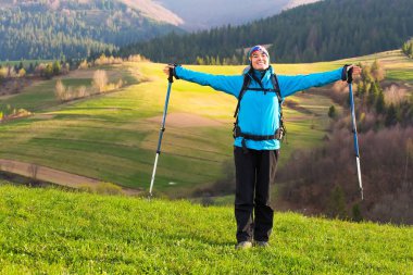 Doğa zammı sağlıklı uzun yürüyüşe çıkan kimse kız. Güzel genç kadın mutlu hiking bir çayır üzerinde oturur. Arka plan güzel mountayns ve mavi gökyüzü bulutlu