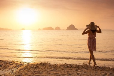 Bir şapka ve kısa elbise mutlu kadın'nde deniz günbatımı sahiptir. Denize, vintage renk arka plan dağlık karstik dağlarda